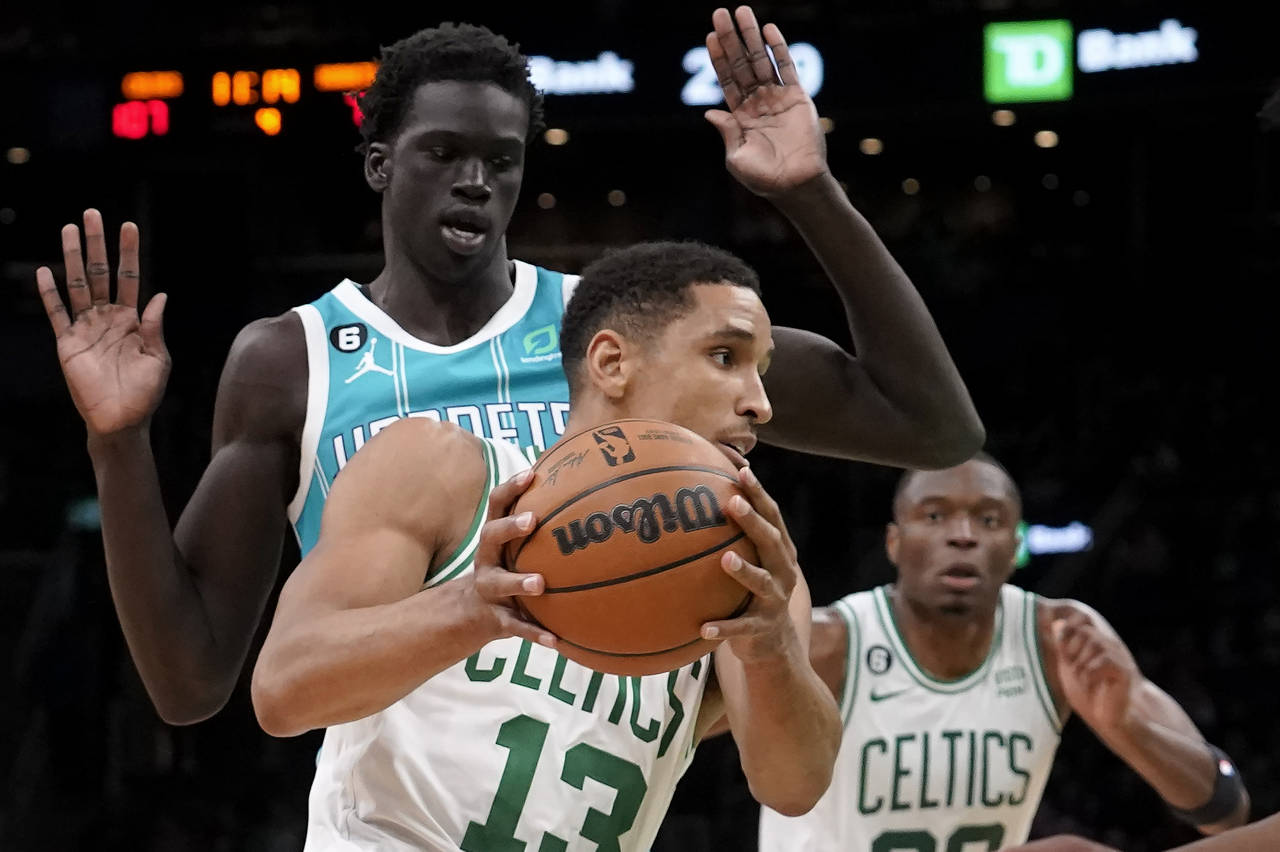 Boston Celtics' Malcolm Brogdon (13) drives toward the basket past Charlotte Hornets' JT Thor, back...