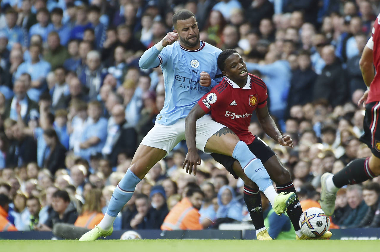Manchester City's Kyle Walker, left, challenges for the ball with Manchester United's Tyrell Malaci...