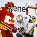 
              Vegas Golden Knights goalie Logan Thompson, center, deflects the puck over the net as Calgary Flames forward Dillon Dube, left, watches during the second period of an NHL hockey game Tuesday, Oct. 18, 2022, in Calgary, Alberta. (Jeff McIntosh/The Canadian Press via AP)
            