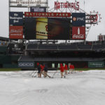 
              A grounds crew removes water from a tarp before a baseball game between the Philadelphia Phillies and Washington Nationals, Sunday, Oct. 2, 2022, in Washington. (AP Photo/Luis M. Alvarez)
            