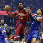 
              Cleveland Cavaliers guard Donovan Mitchell (45) passes between Orlando Magic forward Paolo Banchero (5) and guard Terrence Ross (31) during the first half of a NBA basketball game, Wednesday, Oct. 26, 2022, in Cleveland. (AP Photo/Ron Schwane)
            