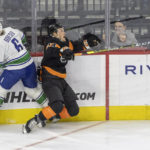 
              Vancouver Canucks right wing Brock Boeser (6) and Philadelphia Flyers defenseman Nick Seeler (24) crash into the boards while trying to control the puck during the second period of an NHL hockey game, Saturday, Oct. 15, 2022, in Philadelphia. (AP Photo/Laurence Kesterson)
            