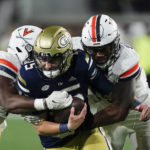 
              Georgia Tech quarterback Zach Gibson (15) is sacked by Virginia's Chico Bennett Jr., right, and Olasunkonmi Agunloye during the second second half of an NCAA college football game Thursday, Oct. 20, 2022, in Atlanta. (AP Photo/John Bazemore)
            