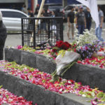
              Flowers are laid by supporters of local soccer club Arema FC, outside Kanjuruhan Stadium where riots broke out on Saturday night in Malang, East Java, Indonesia, Sunday, Oct. 2, 2022. Panic at the soccer match between Arema FC and Persebaya of Surabaya city left over 150 people dead, most of whom were trampled to death after police fired tear gas to dispel the riots. (AP Photo/Trisnadi)
            