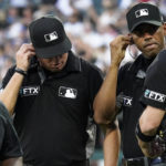 
              Umpire Cory Blaser, second from left, Edwin Moscoso, second from right, and Dan Bellino check their headsets after the first inning of a baseball game in Chicago, Friday, July 22, 2022. A policy change implemented at the beginning of the season, designed to explain on-field call challenges and outcomes, equipped umpires with tiny wireless microphones and — for the first time in baseball history — introduced their amplified voices to ballpark speakers, to the fans in their seats and to the world at home. (AP Photo/Nam Y. Huh)
            