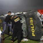 
              Officers examine a damaged police vehicle following a clash between supporters of two Indonesian soccer teams at Kanjuruhan Stadium in Malang, East Java, Indonesia, Saturday, Oct. 1, 2022. Clashes between supporters of two Indonesian soccer teams in East Java province killed over 100 fans and a number of police officers, mostly trampled to death, police said Sunday. (AP Photo/Yudha Prabowo)
            