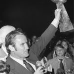 
              FILE- Miami Dolphins coach Don Shula waves the Vince Lombardi trophy, Jan. 15, 1973, as the team arrives in Miami after winning the Super Bowl. Shula's son David looks on at right. The Dolphins defeated the Washington Redskins in Super Bowl VII to become the first and still, the only team to have an undefeated season. (AP Photo/File)
            