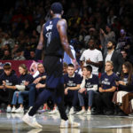 
              Fans with matching shirts look on as Brooklyn Nets guard Kyrie Irving (11) walks by during the first half of an NBA basketball game against the Indiana Pacers, Monday, Oct. 31, 2022, in New York. (AP Photo/Jessie Alcheh)
            