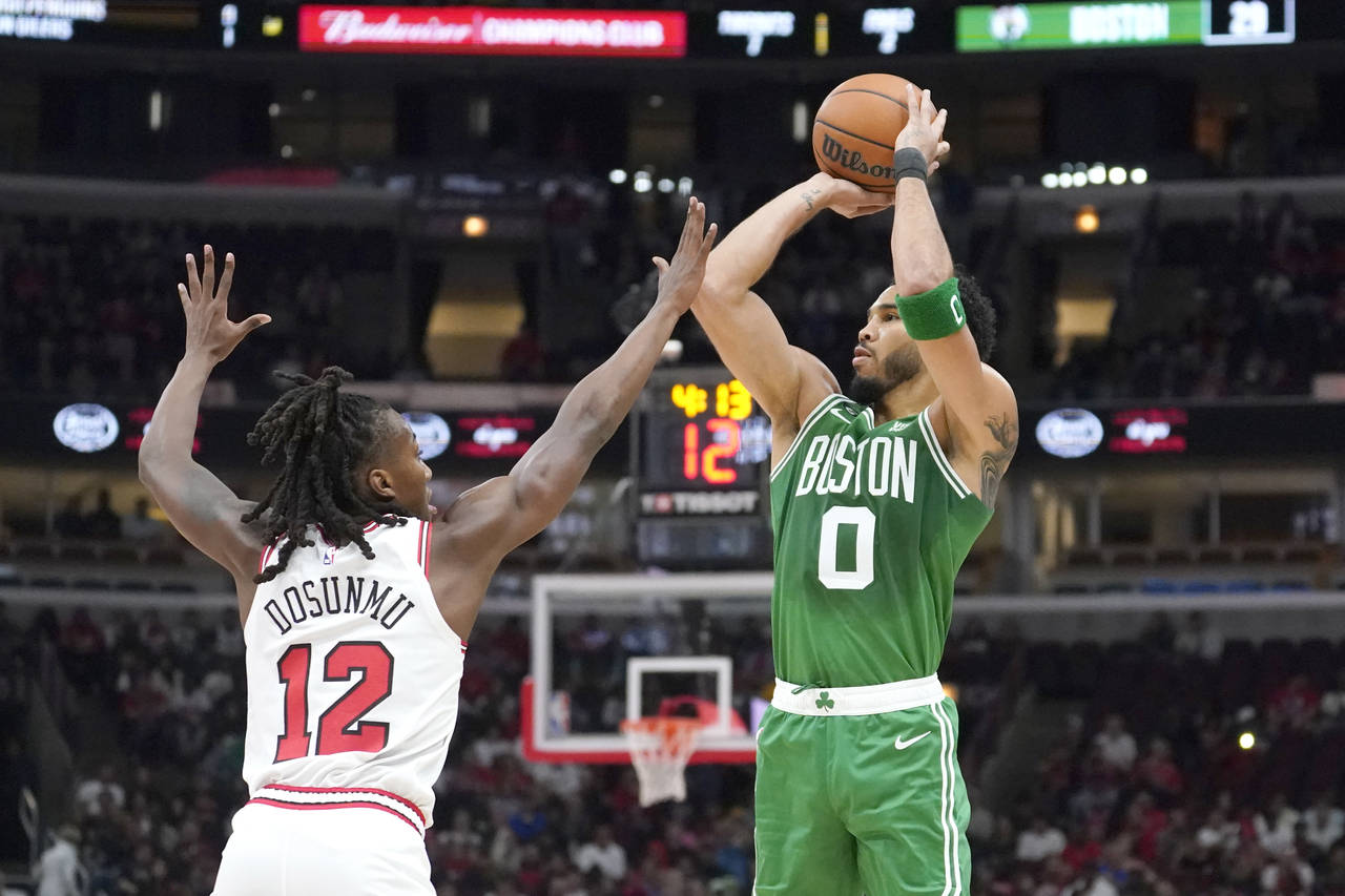 Boston Celtics' Jayson Tatum (0) shoots as Chicago Bulls' Ayo Dosunmu defends during the first half...