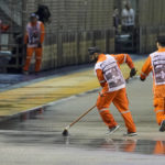 
              Marshals clear the track of surface water after rain delays the start of the Singapore Formula One Grand Prix, at the Marina Bay City Circuit in Singapore, Sunday, Oct. 2, 2022. (AP Photo/Vincent Thian)
            