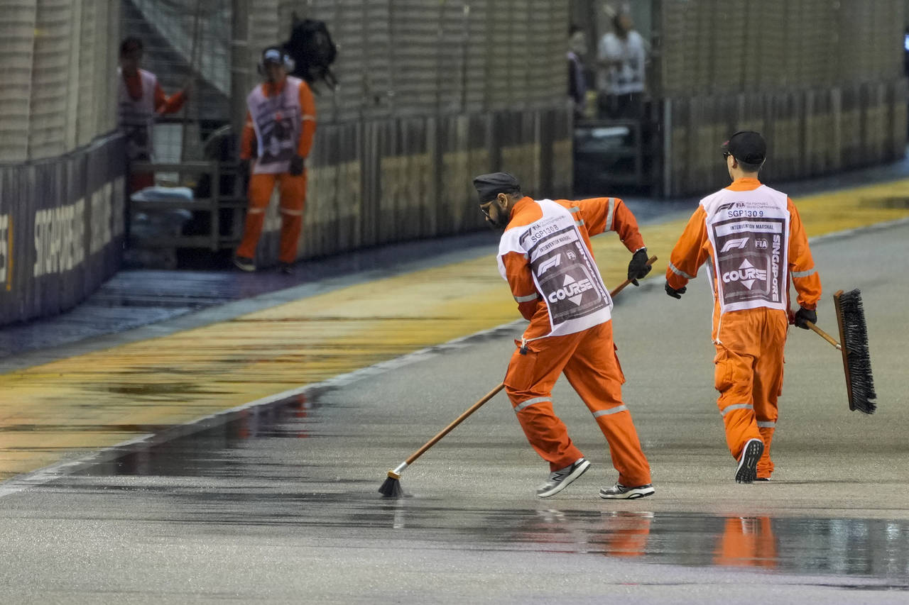 Marshals clear the track of surface water after rain delays the start of the Singapore Formula One ...