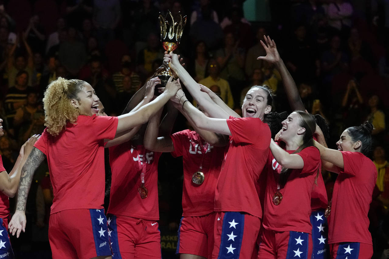 Gold medalists the United States hold their trophy aloft as they celebrate on the podium after defe...