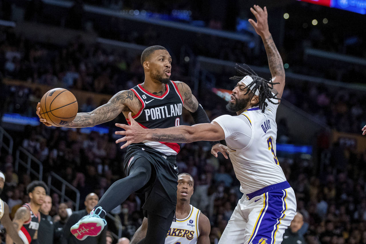 Portland Trail Blazers guard Damian Lillard, left, passes the ball away from Los Angeles Lakers for...