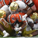 
              Syracuse running back Sean Tucker (34) is tackled by Notre Dame defenders during the first half of an NCAA college football game in Syracuse, N.Y., Saturday, Oct. 29, 2022. (AP Photo/Adrian Kraus)
            