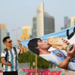 
              Argentinian fan holds up banner with soccer legend Diego Maradona as the fan zone opens ahead of the FIFA World Cup in Doha, Qatar, Saturday, Nov. 19, 2022. (AP Photo/Petr David Josek)
            