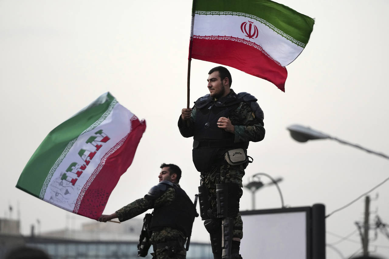 Two anti-riot police officers wave the Iranian flags during a street celebration after Iran defeate...
