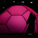 
              A woman wearing a traditional Qatari dress uses a cell phone to capture images in front of a soccer ball lit up in the colors of the Qatar flag during the FIFA fan festival at the World Cup soccer tournament in Doha, Qatar, Tuesday, Nov. 22, 2022. (AP Photo/Julio Cortez)
            