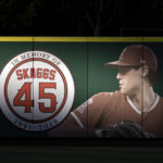 
              FILE - In this July 17, 2019, file photo, an image and logo memorializing former Los Angeles Angels pitcher Tyler Skaggs are displayed on the outfield wall in Anaheim, Calif. A California judge is allowing a lawsuit to proceed against the Angels over the drug-related death of Skaggs. (AP Photo/Kyusung Gong, File)
            