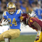 
              UCLA running back Zach Charbonnet, left, fends off Southern California defensive back Max Williams during the first half of an NCAA college football game Saturday, Nov. 19, 2022, in Pasadena, Calif. (AP Photo/Mark J. Terrill)
            