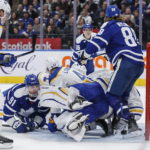 
              Toronto Maple Leafs' John Tavares (91) dives in front of the net as William Nylander (88) scores on Buffalo Sabres goaltender Ukko-Pekka Luukkonen during the second period of an NHL hockey game in Toronto on Saturday, Nov. 19, 2022. (Cole Burston/The Canadian Press via AP)
            