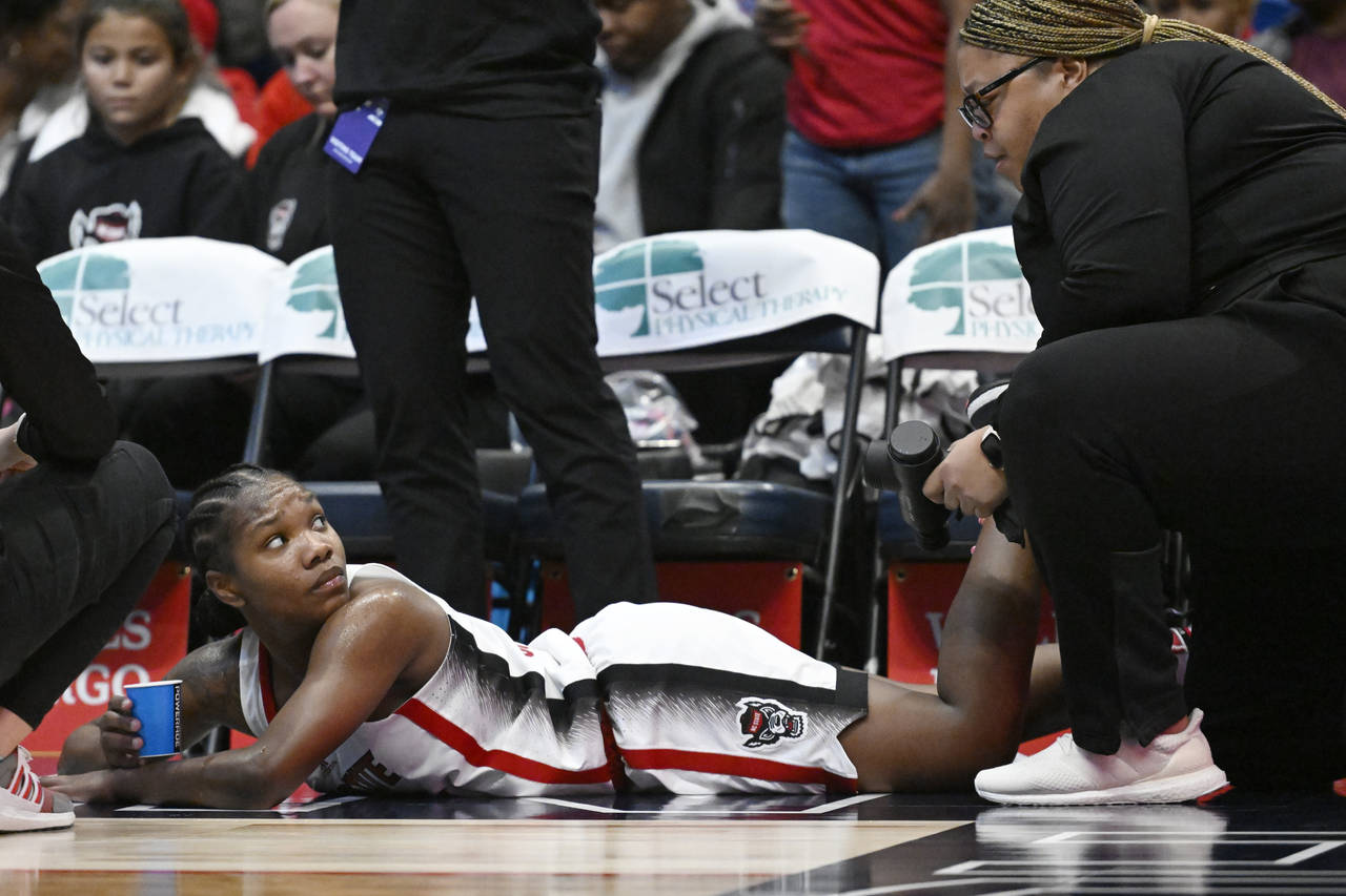 North Carolina State's Diamond Johnson, left, has her leg tended to by athletic trainer Brittany Bl...
