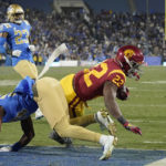 
              Southern California running back Darwin Barlow, right, dives in for a touchdown as UCLA defensive back Jaylin Davies, lower left, defends along with defensive back Kenny Churchwell III during the second half of an NCAA college football game Saturday, Nov. 19, 2022, in Pasadena, Calif. (AP Photo/Mark J. Terrill)
            