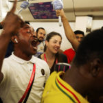 
              Associated Press correspondent Isabel DeBre, center, smiles as Ghana fans celebrate their win in the Doha Metro in Doha, Qatar, Monday, Nov. 28, 2022. With Qatar's World Cup the most compact tournament in the competition's history, DeBre set out to see four matches in one day. (AP Photo/Jon Gambrell)
            