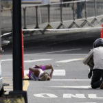 
              Daniel Do Nascimento, of Brazil, left, lays on the pavement after collapsing in the Bronx borough during the New York City Marathon, Sunday, Nov. 6, 2022, in New York. (AP Photo/Julia Nikhinson)
            