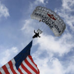 
              A parachute team member enters the stadium with an American flag during the national anthem prior to an NCAA college football game between Tulane and Cincinnati, Friday, Nov. 25, 2022, in Cincinnati. (AP Photo/Aaron Doster)
            