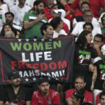 
              Iranian soccer fan holds up sign reading Woman Life Freedom Masha Amini prior to the World Cup group B soccer match between England and Iran at the Khalifa International Stadium in in Doha, Qatar, Monday, Nov. 21, 2022. (AP Photo/Alessandra Tarantino)
            