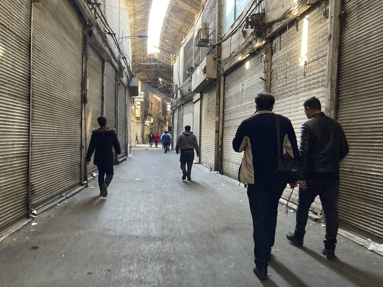 People walk through closed shops of Tehran's Grand Bazaar, Iran, Tuesday, Nov. 15, 2022. Many shops...