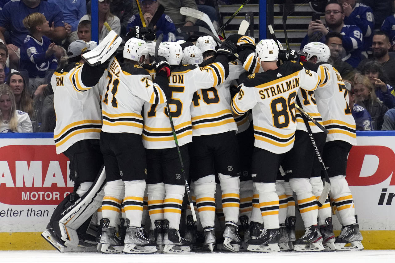 Boston Bruins players mob center Patrice Bergeron after Bergeron assisted on a goal by left wing Br...