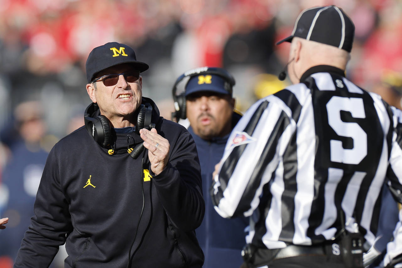 Michigan head coach Jim Harbaugh argues with a game official during the second half of an NCAA coll...