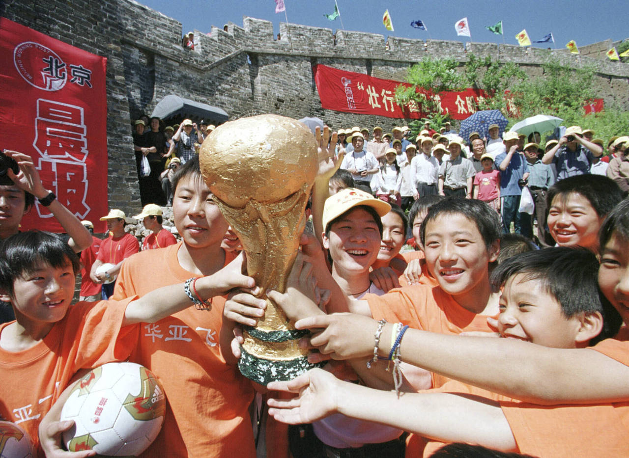 FILE - Chinese children pose with a replica of the World Cup trophy on the Great Wall of China at J...