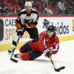 
              Washington Capitals right wing T.J. Oshie (77) reaches for the puck in front of Philadelphia Flyers defenseman Justin Braun (61) during the first period of a NHL hockey game, Wednesday, Nov. 23, 2022, in Washington. (AP Photo/Nick Wass)
            