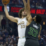 
              Cleveland Cavaliers center Robin Lopez (33) shoots against Minnesota Timberwolves center Karl-Anthony Towns (32) during the first half of an NBA basketball game, Sunday, Nov. 13, 2022, in Cleveland. (AP Photo/Ron Schwane)
            