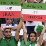 
              Iranian soccer fans hold up signs reading Woman Life Freedom and Freedom For Iran, prior to the World Cup group B soccer match between England and Iran at the Khalifa International Stadium in in Doha, Qatar, Monday, Nov. 21, 2022. (AP Photo/Alessandra Tarantino)
            