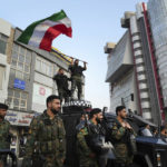 
              An anti-riot police officer waves a representation of the Iranian flag during a street celebration after Iran's national soccer team defeated Wales in Qatar's World Cup, at Sadeghieh Sq. in Tehran, Iran, Friday, Nov. 25, 2022. Iran's political turmoil has cast a shadow over Iran's matches at the World Cup, spurring tension between those who back the team and those who accuse players of not doing enough to support the protests that started Sept. 16 over the death of a 22-year-old woman in the custody of the morality police. (AP Photo/Vahid Salemi)
            