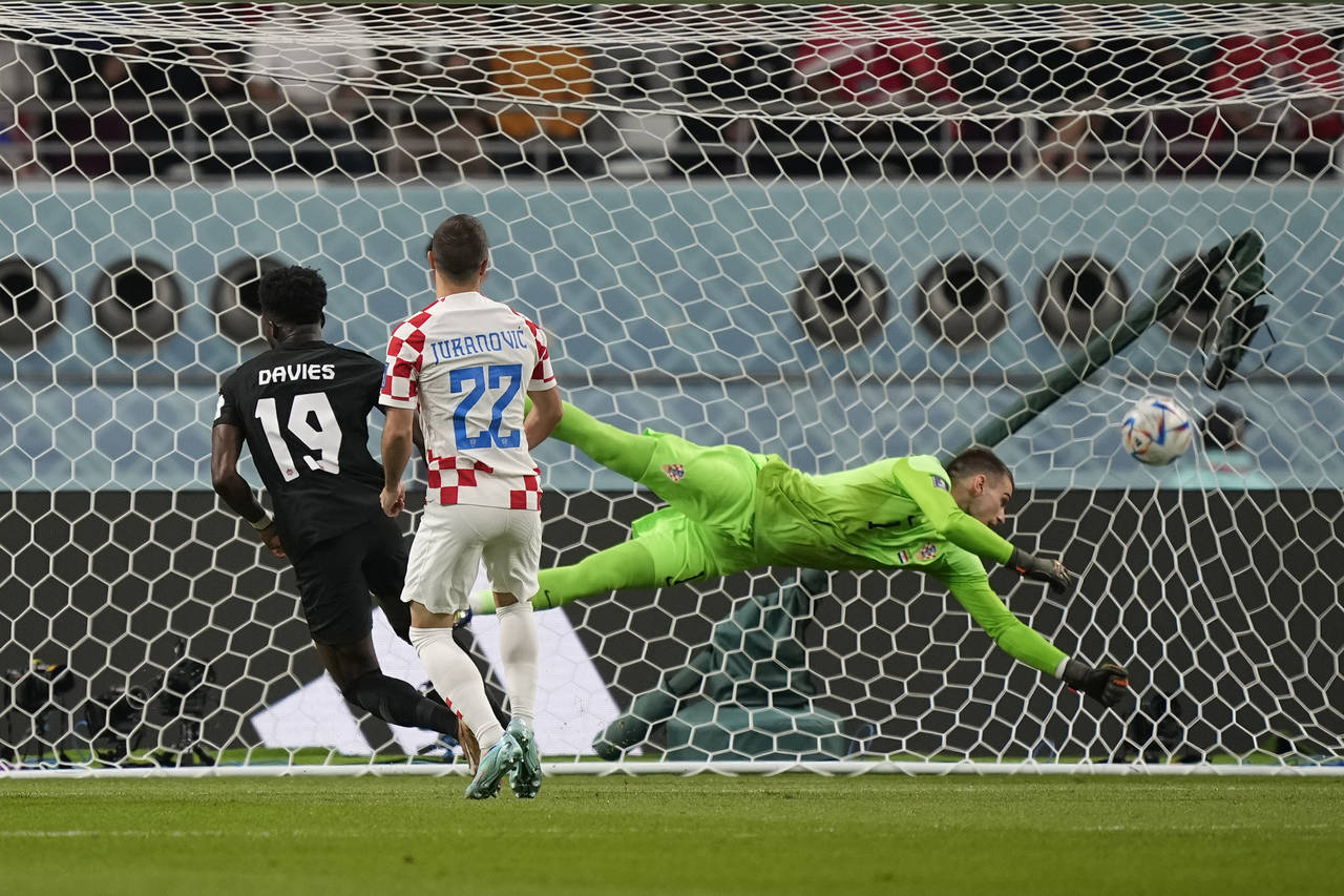 Canada's Alphonso Davies, left, scores the opening goal during the World Cup group F soccer match b...