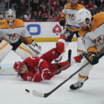 
              Detroit Red Wings center Oskar Sundqvist (70) tries to pass the puck in front of Nashville Predators goaltender Kevin Lankinen (32) as Dante Fabbro (57) looks to intercept in the second period of an NHL hockey game Wednesday, Nov. 23, 2022, in Detroit. (AP Photo/Paul Sancya)
            