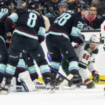 
              Minnesota Wild forward Frederick Gaudreau, second from right, attempts to get to the puck against Seattle Kraken forward Matty Beniers, far left, defenseman Cale Fleury, second from left, and defenseman Carson Soucy (28) during the second period of an NHL hockey game Friday, Nov. 11, 2022, in Seattle. (AP Photo/Stephen Brashear)
            