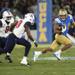 
              UCLA running back Zach Charbonnet, right, avoids Arizona linebacker Sterling Lane II, left, and linebacker Jerry Roberts during the first half of an NCAA college football game Saturday, Nov. 12, 2022, in Pasadena, Calif. (AP Photo/Mark J. Terrill)
            
