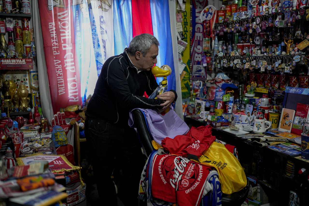 Osvaldo Santander stands with his soccer collection in his home during an interview with The Associ...