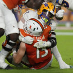
              Miami quarterback Jake Garcia (13) is tackled by Pittsburgh linebacker SirVocea Dennis (7) during the first half of an NCAA college football game, Saturday, Nov. 26, 2022, in Miami Gardens, Fla. (AP Photo/Lynne Sladky)
            
