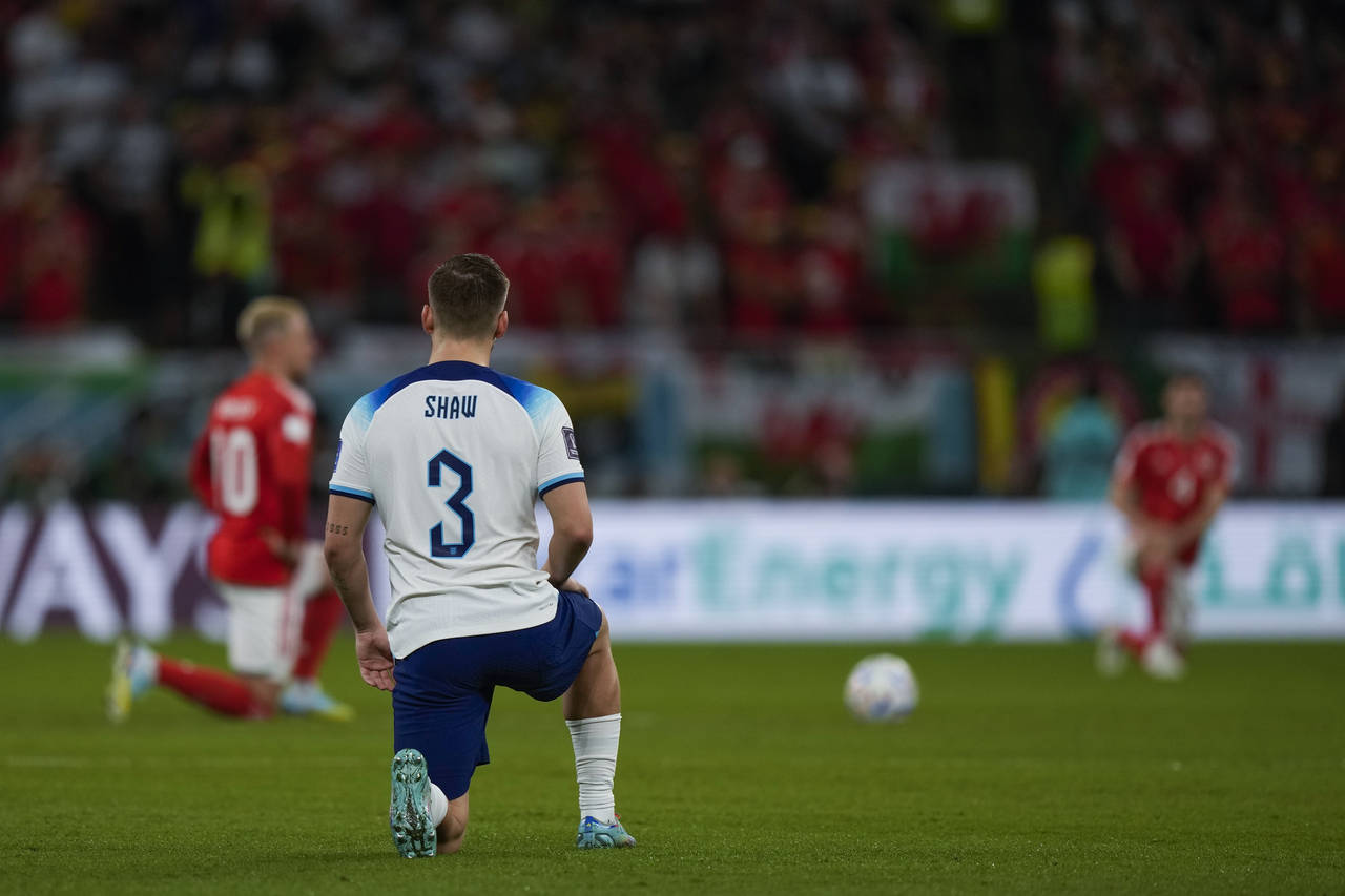 England's Luke Shaw knees along Wales players, background, just before the kick off of the World Cu...