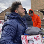 
              Michigan running back Blake Corum carries a tray containing a turkey, vegetables and other items during a giveaway event outside a school in Ypsilanti, Mich., on Sunday, Nov. 20, 2022. Corum took part in the charitable effort a day after hurting his knee and less than a week before his third-ranked Wolverines play No. 2 Ohio State. (AP Photo/Mike Householder)
            