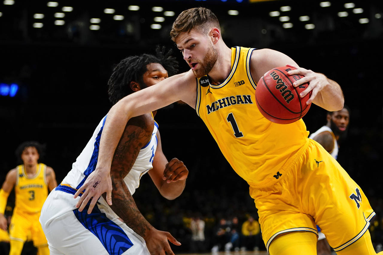 Michigan's Hunter Dickinson, right, drives past Pittsburgh's John Hugley IV during the first half o...