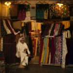 
              A clothes shop seller drinks tea as he waits for customers in Souq Waqif market, one day ahead of the World Cup kick off, in Doha, Qatar, Saturday, Nov. 19, 2022. (AP Photo/Francisco Seco)
            