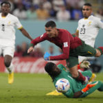 
              Portugal's Cristiano Ronaldo, up, falls over Ghana's goalkeeper Lawrence Ati-Zigi during the World Cup group H soccer match between Portugal and Ghana, at the Stadium 974 in Doha, Qatar, Thursday, Nov. 24, 2022. (AP Photo/Darko Bandic)
            