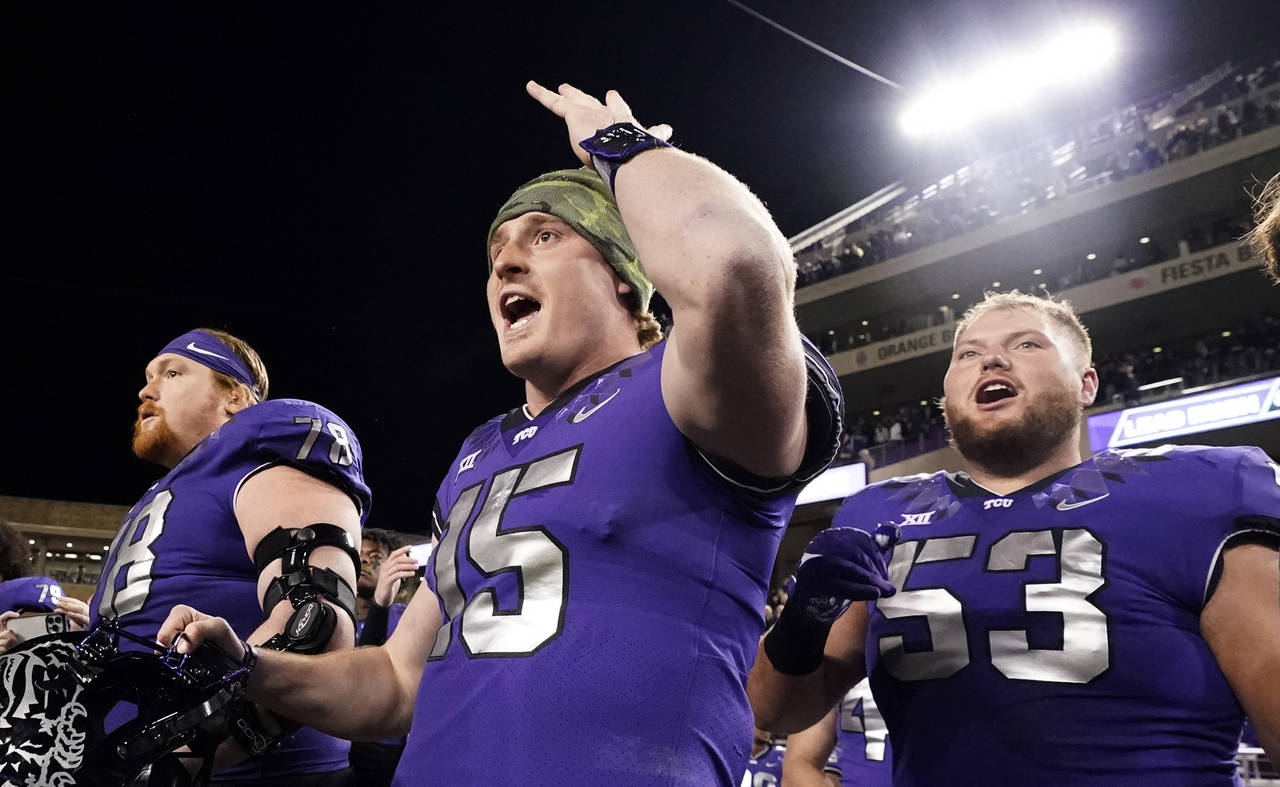 TCU quarterback Max Duggan (15) reacts on the sidelines with teammates guards John Lanz (53) and We...